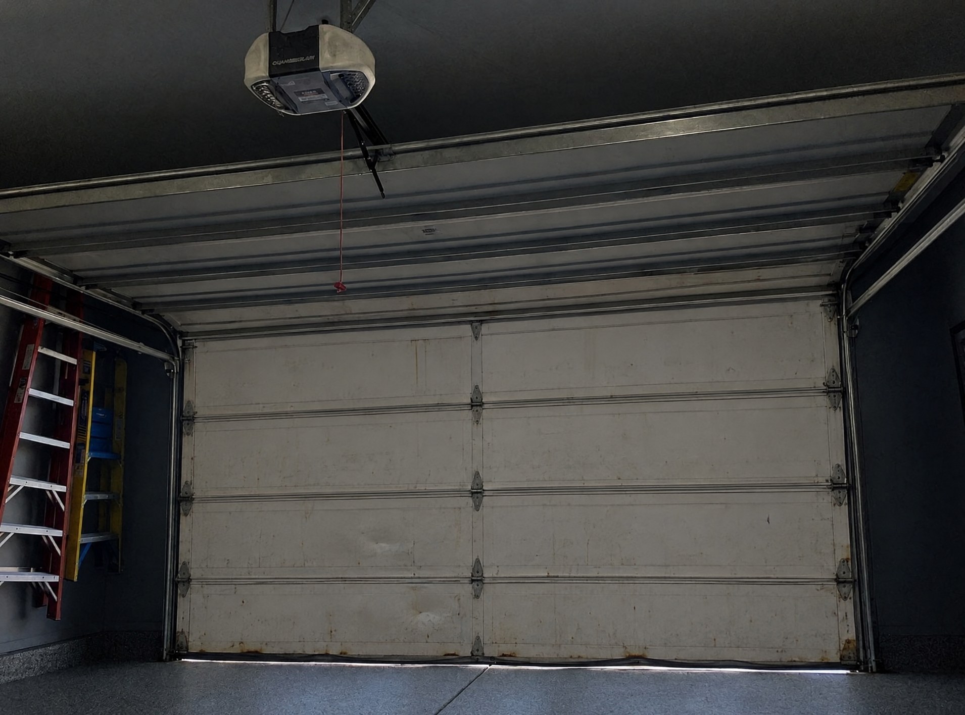 Before: old dented white steel garage door from inside the garage