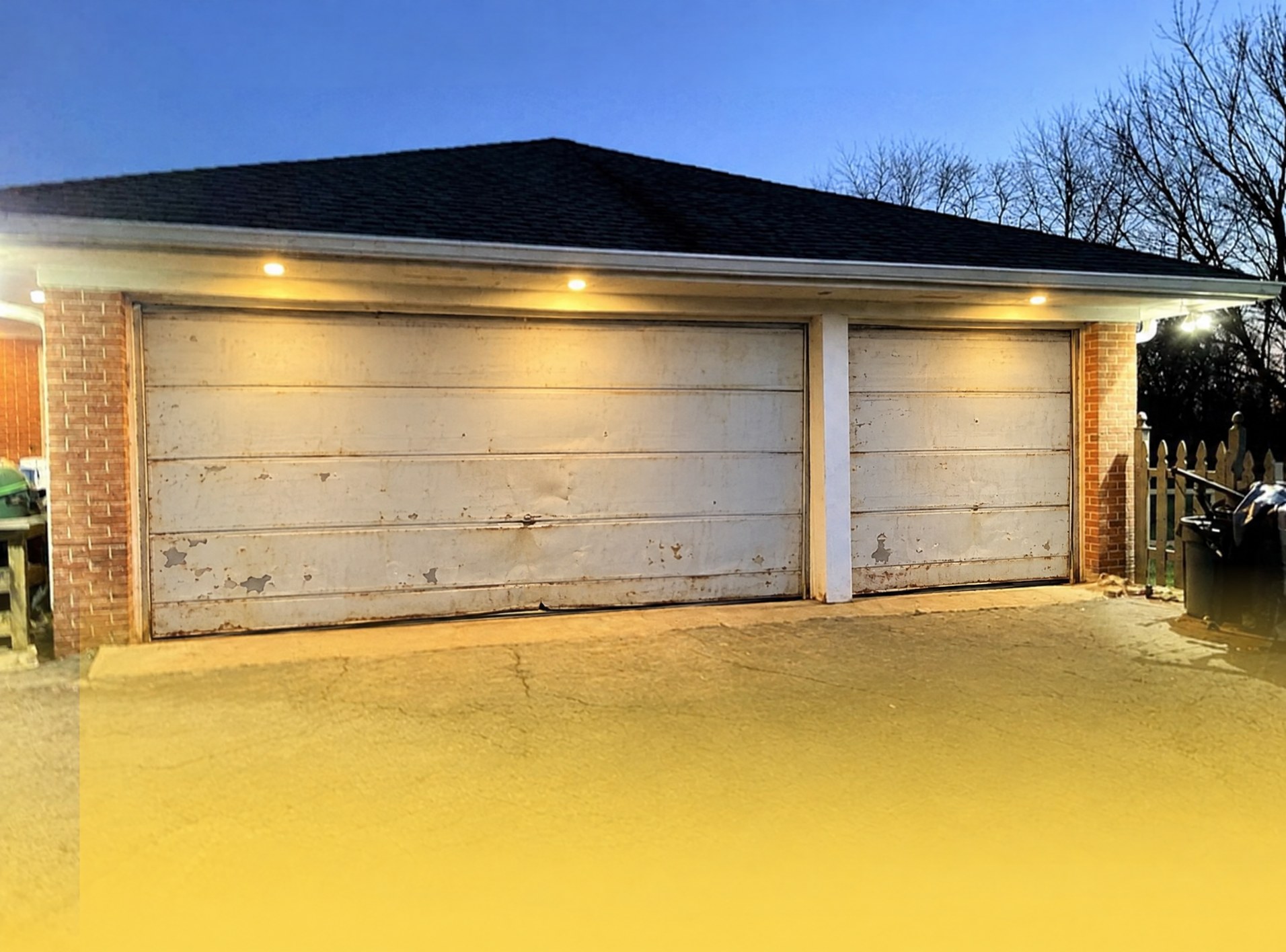 Before: worn, peeling white garage doors on a brick two-car garage